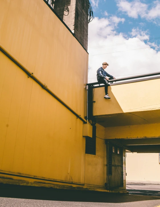 a man sitting on top of a tall yellow building