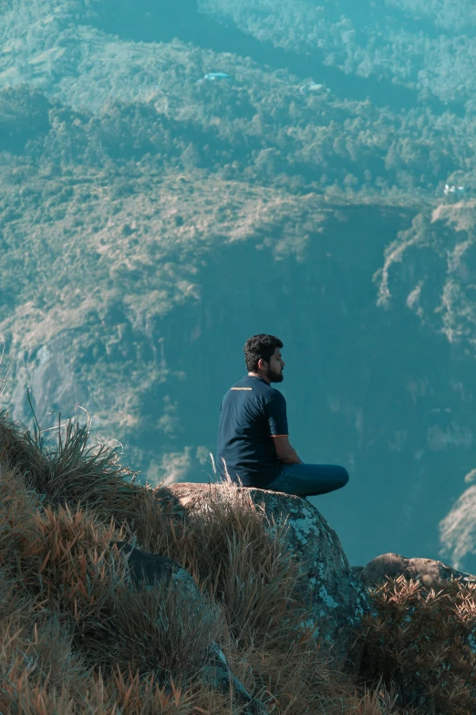 a man sits on a mountain looking over a valley