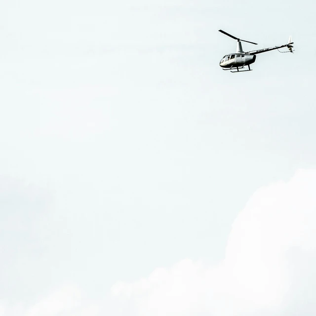 a helicopter flying through the air on a cloudy day