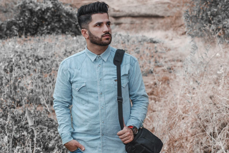 a man standing in a field holding his bag