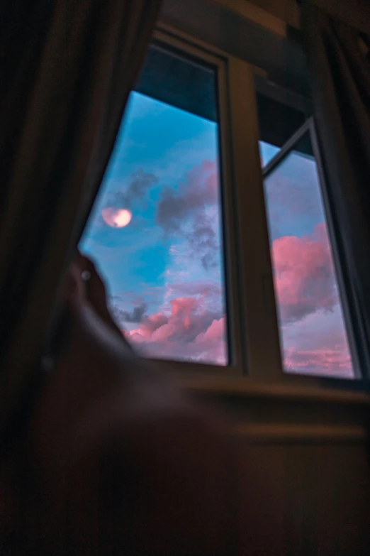 someone is looking out the window at a moon setting