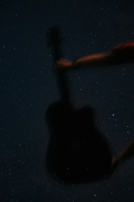 an acoustic guitar hanging upside down against a dark background