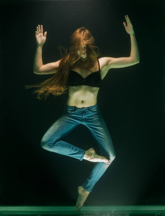 a woman floating in water with her hands up and  in the air
