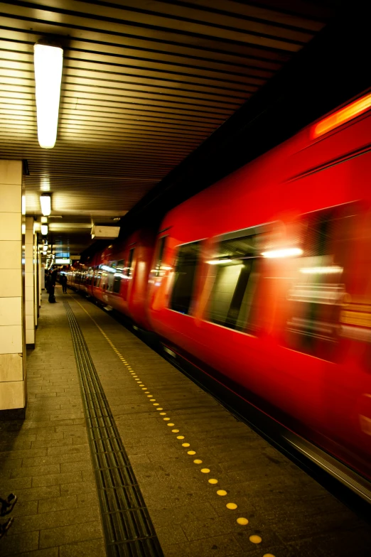 red train at subway station with moving commuters