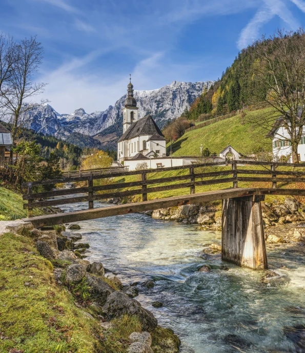 a church and bridge in the middle of a mountain valley