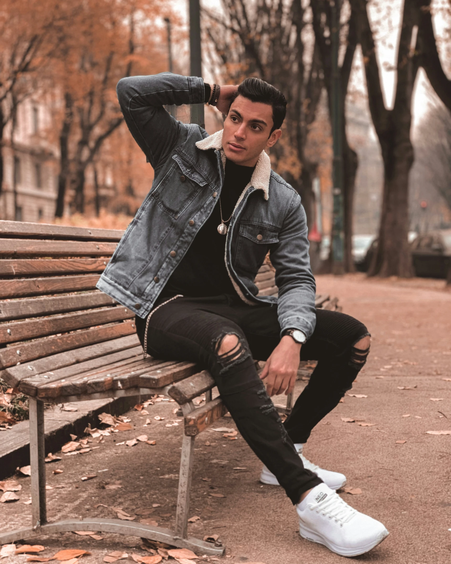 a man is sitting on a park bench in autumn