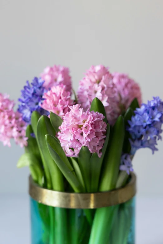 an arrangement of purple and purple flowers in a teal vase