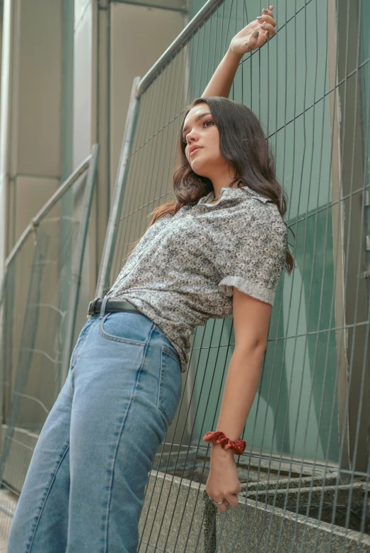 the woman is leaning against a fence, reaching on soing