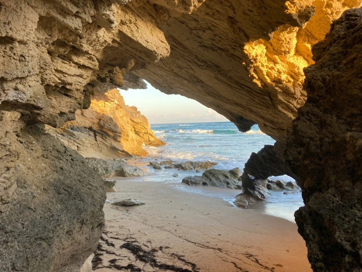 a sandy beach next to the ocean with small caves