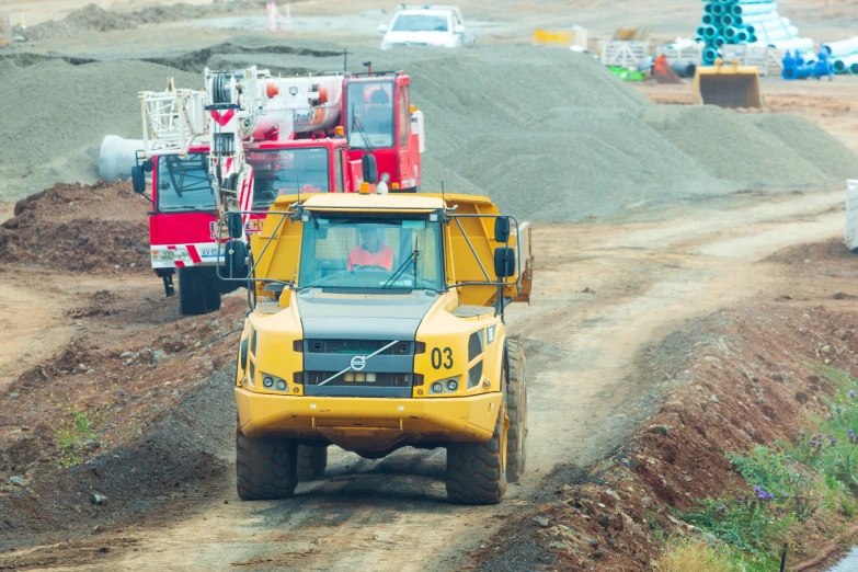 trucks are driving through some dirt and gravel mounds