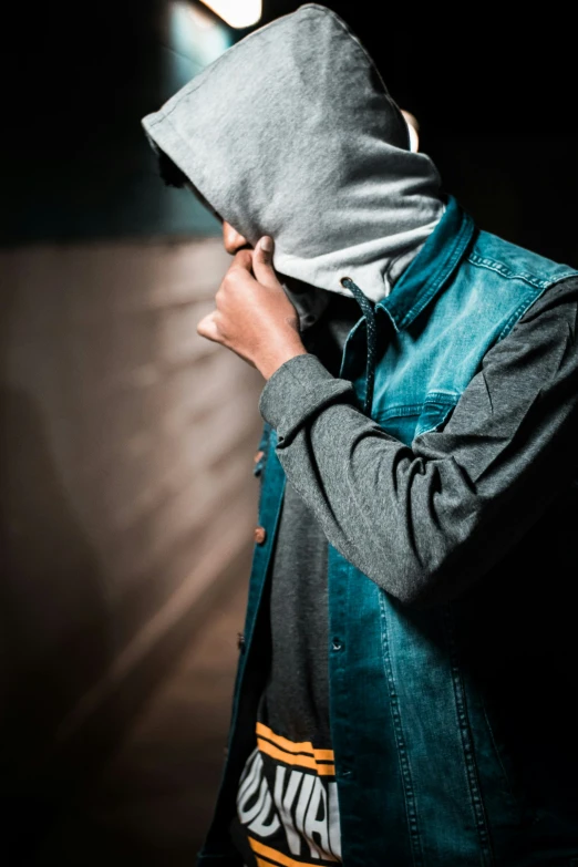 a man in the dark holding a hood over his face