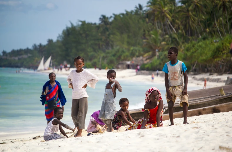 children at the beach, some on the sand and others on the water