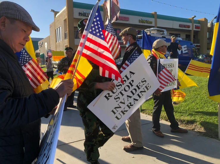a person holds american and spanish flags as they take part in a protest