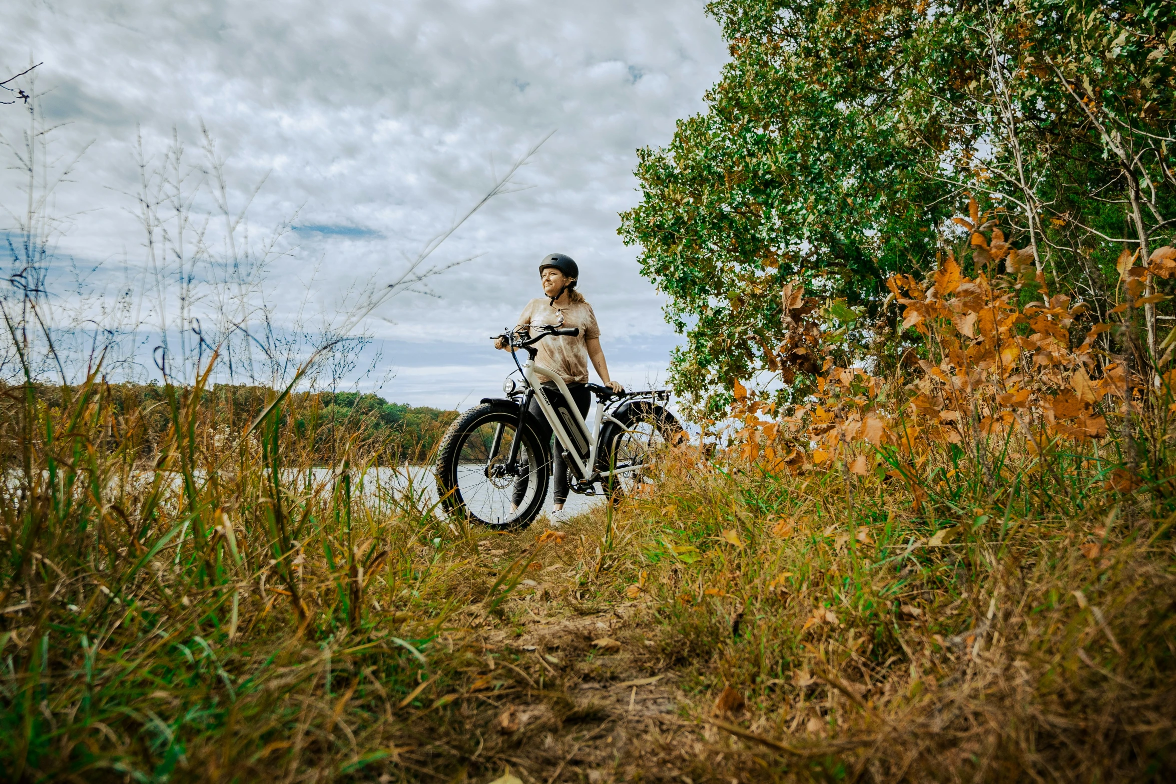 an elderly woman with a bicycle riding through the wild