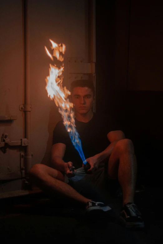 a man sits on the ground holding a burning stick