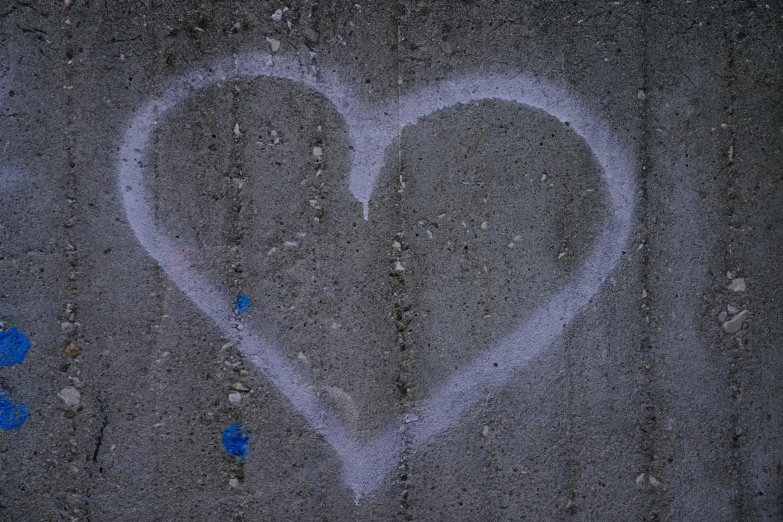 the word love in the center of a heart drawn on a piece of concrete