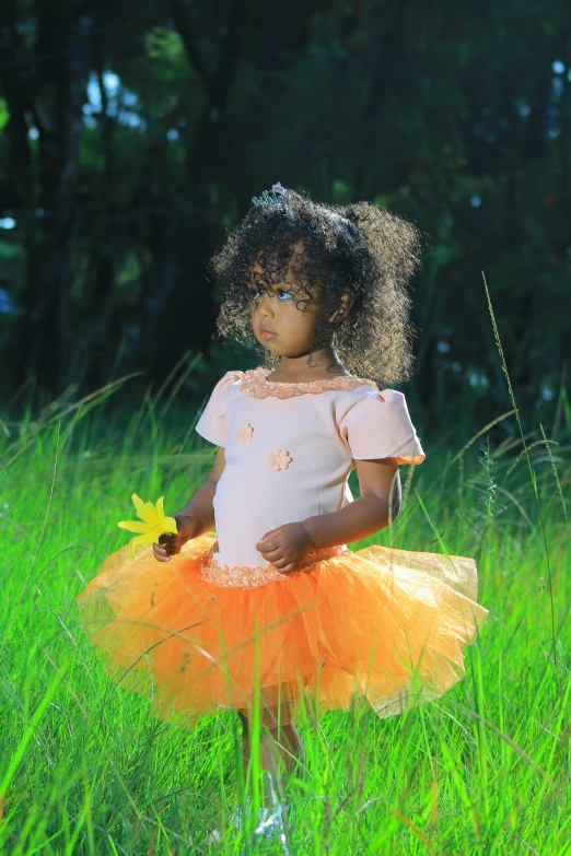 an african american baby is dressed in an orange and pink dress