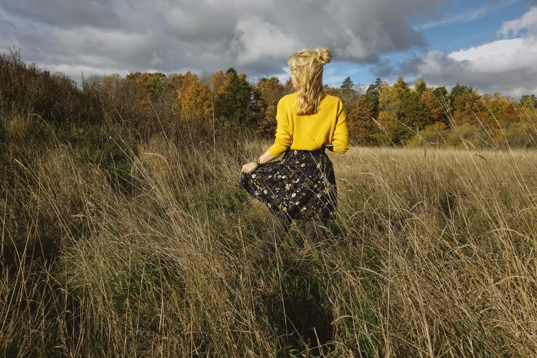 a woman walking across a grass covered field