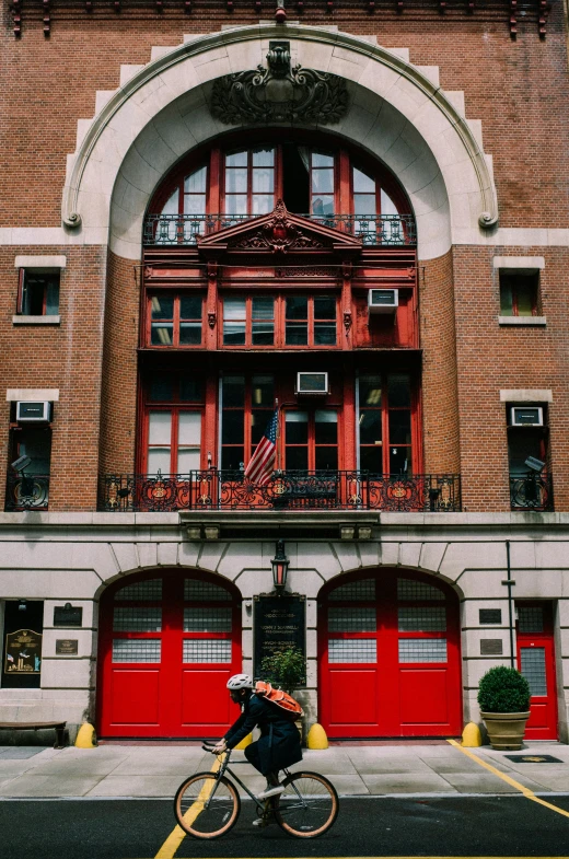 a person riding a bicycle past red doors