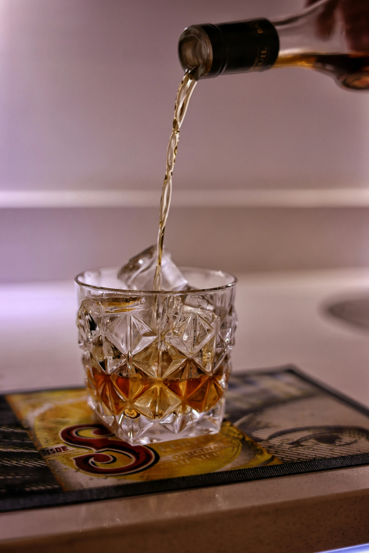 someone pouring a glass of liquor with ice