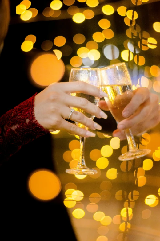 people clinking glasses of champagne over a table with many lights