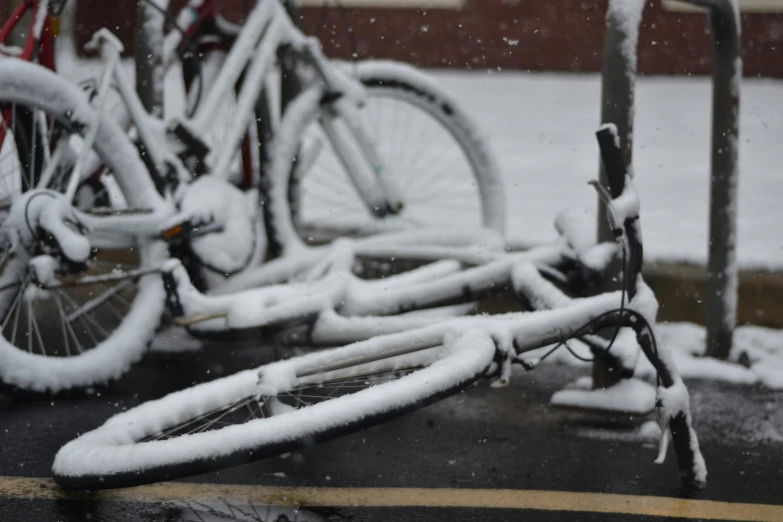 several bikes locked to the side of the building covered in snow