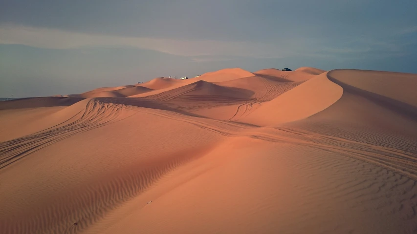 a large sand dune with cars in the distance