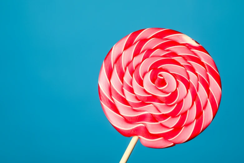 a pink and white lollipop is on a stick