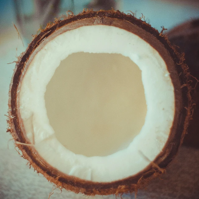 a coconut sliced into three halves with its inside brown and white interior