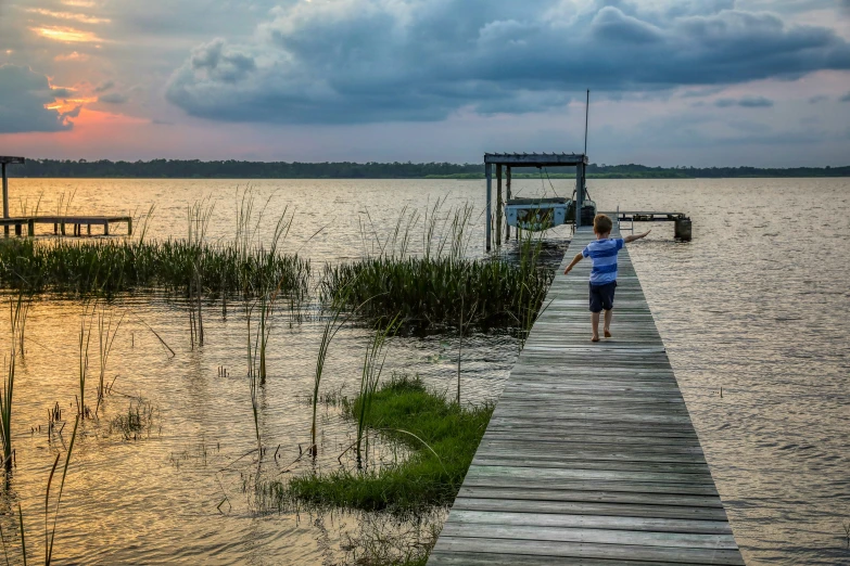 the girl is walking up the pier toward the ocean