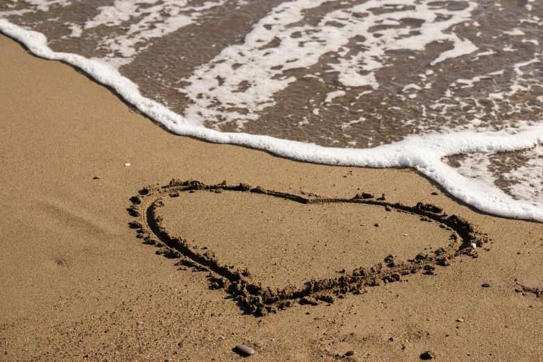 the heart is drawn on the sandy beach near the ocean