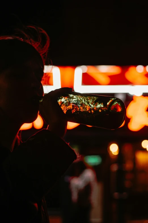 a woman drinking from a  dog bun at night