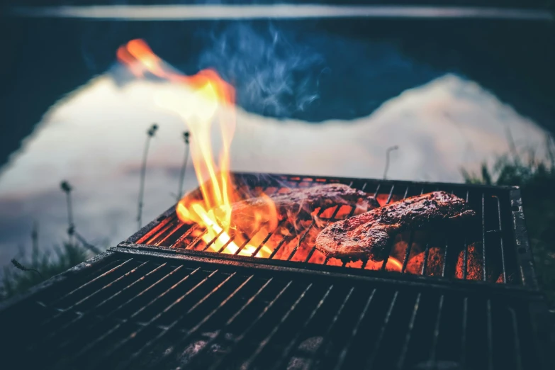 a burger is being grilled on the grill with flames