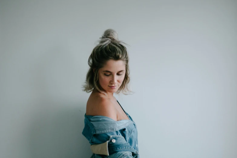 a young woman with her hands on her hip while she leans against a wall