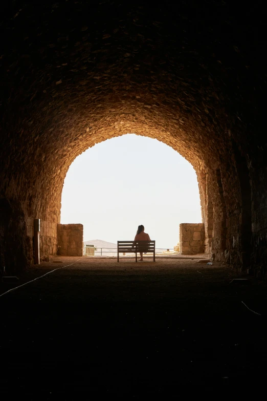 a person sitting on a bench in a tunnel