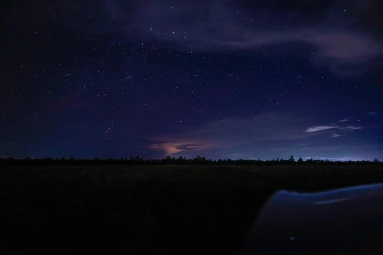 the night sky is lit up over a field