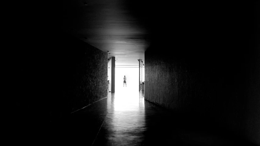 a person standing in the light at an end of a dark corridor