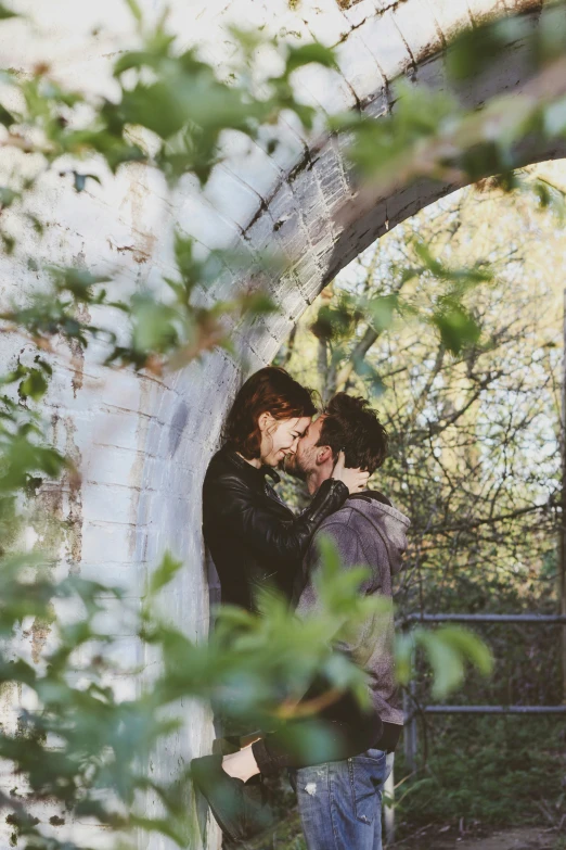 two people hugging in an archway surrounded by trees