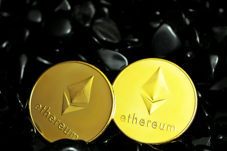 ether coin laying on black pebbles with black rocks