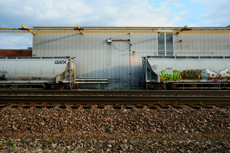 two freight cars sitting in front of an industrial building