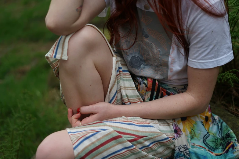 a girl with long red hair sits outdoors