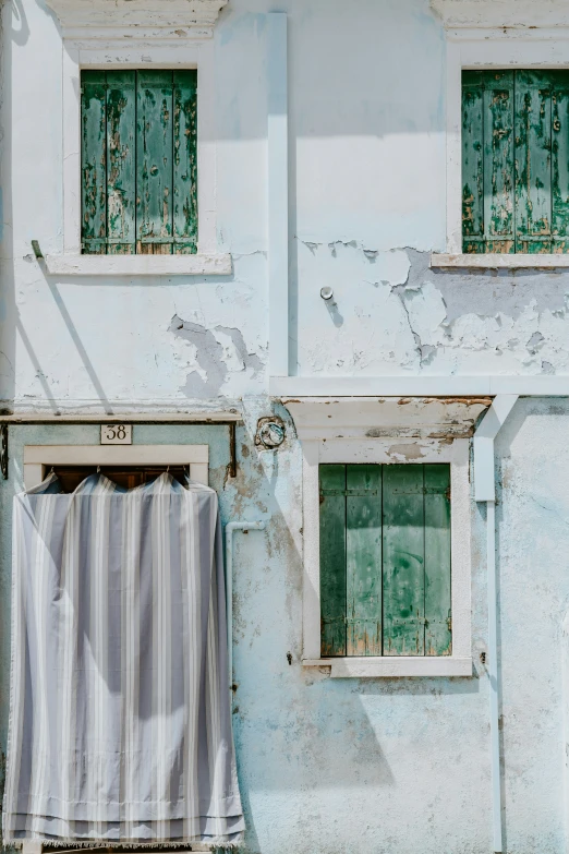 an old building with two windows and a striped curtain