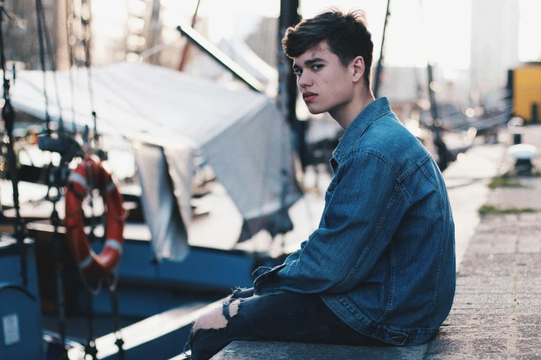 a young man is sitting on the edge of a boat