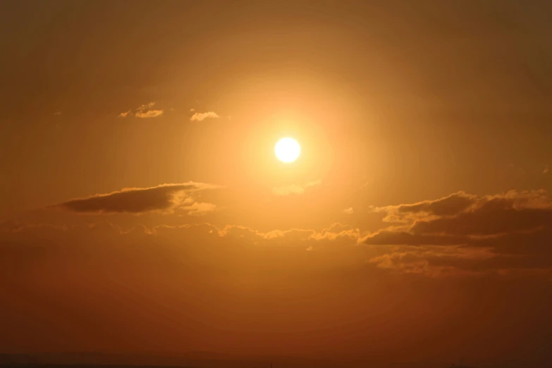 the sun shining over some distant clouds in a sky