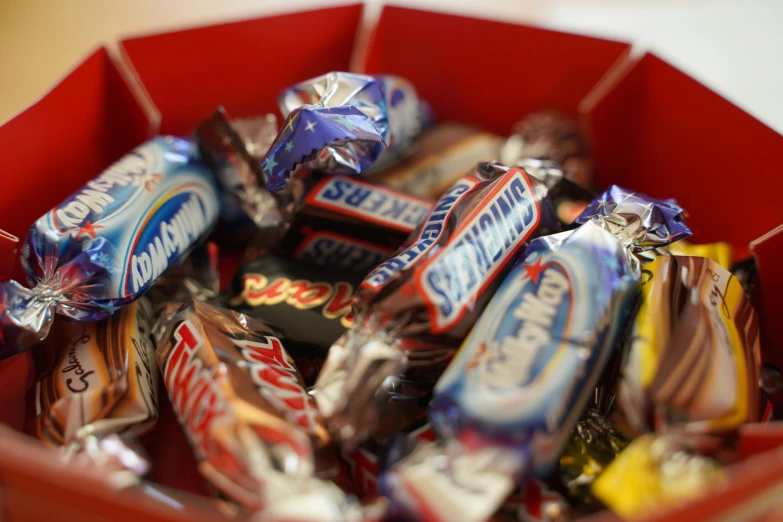 a red bowl of assorted candy bars