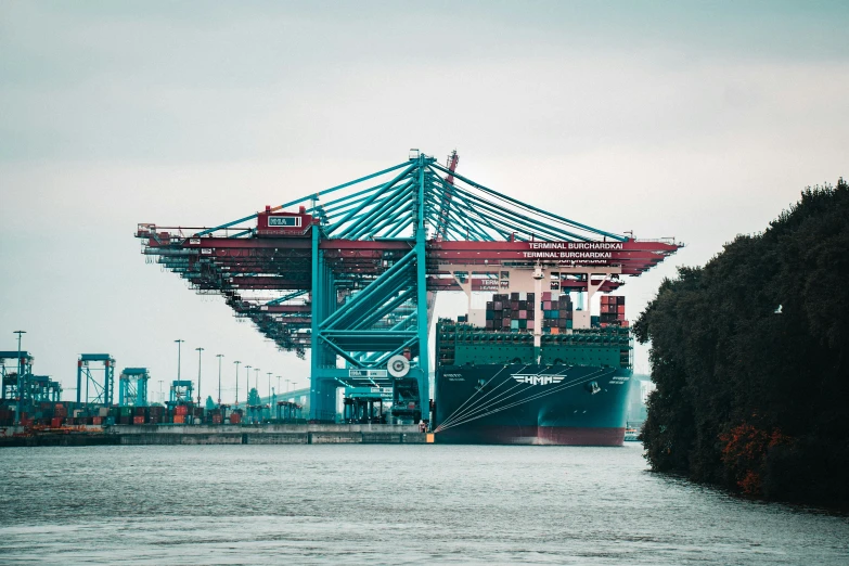 cargo ship docked at port under a bridge