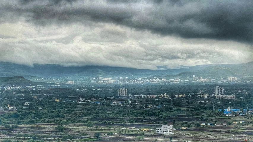 a view of city in a distance under the dark clouds