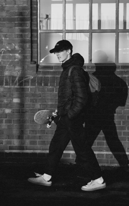 two people holding skateboards walking against a wall