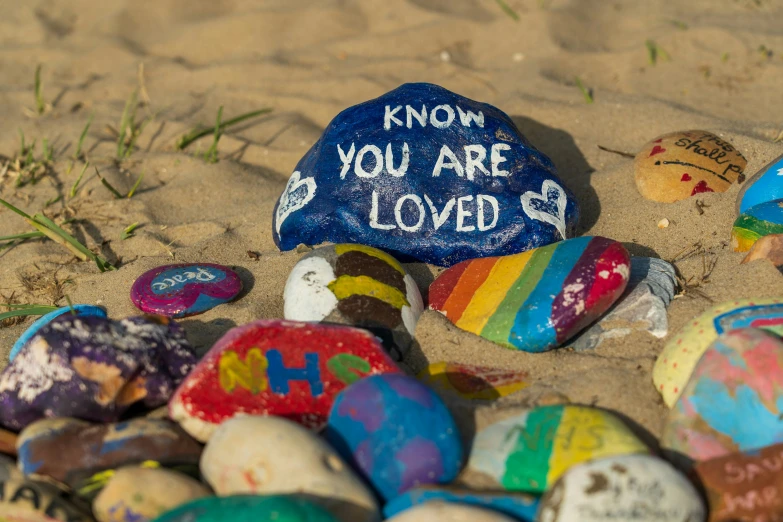 colorful rocks with writing written on them are all on the beach