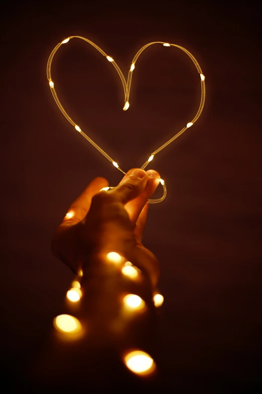 a person holding a string with the lights of a heart